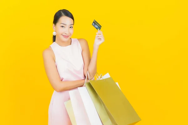 亚洲年轻貌美的女人带着黄色背景的购物袋微笑 — 图库照片