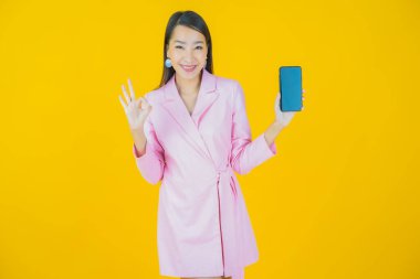 Renkli arka planda akıllı cep telefonuyla güzel Asyalı kadın gülümsemesi