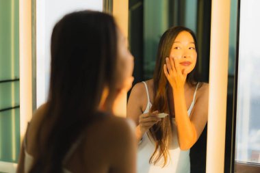 Güzel bir Asyalı kadın portresi. Banyo içinde yüzüne ve yüzüne krem sür.