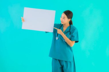 Fotokopi için boş kâğıt tahtası olan güzel Asyalı genç doktor kadın hastane ve klinikteki sağlık hizmetleri konseptinde mavi izole edilmiş arka plan.