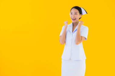 Güzel Asyalı genç Taylandlı hemşirenin portresi klinikteki ve hastanedeki hastalar için sarı izole edilmiş arka planda birçok eylem çalışmasında yer alıyor.