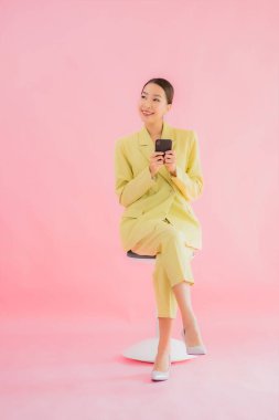 Güzel Asyalı iş kadını portresi. Arka planda kahve fincanı ve akıllı cep telefonu kullanıyor.