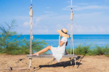 Güzel bir Asyalı kadının portresi. Rahatlayın. Deniz kıyısında salıncakta sallanın.