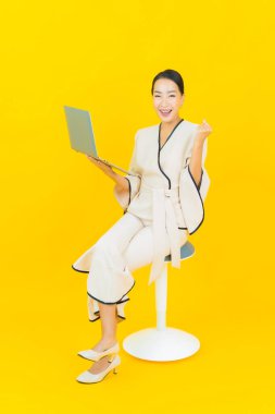 Sarı arka planda bilgisayar bilgisayarı olan güzel bir iş kadını portresi.