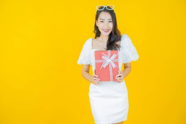 Güzel bir Asyalı kadının portresi. Arka planda kırmızı hediye kutusuyla gülümsüyor.