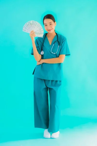 肖像美しい若いアジアの医師の女性ショーお金と現金オン青隔離された背景 — ストック写真