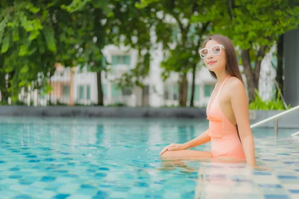 美丽的年轻亚洲女人在酒店度假胜地的室外游泳池边悠闲自在地笑着 — 图库照片