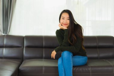Güzel bir portre. Genç Asyalı kadın. Oturma odasındaki kanepede rahatla.