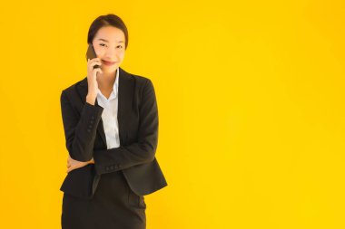 Portre güzel genç Asyalı kadın akıllı cep telefonu ve kahve fincanı ile izole edilmiş sarı arka planda
