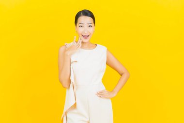 Asyalı güzel bir kadının portresi. Sarı arka planda hareketli gülümsüyor.