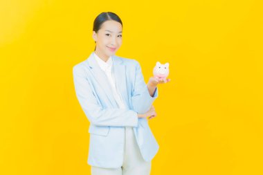 Renkli arka planda domuz kumbarası olan güzel Asyalı kadın portresi