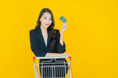 Renkli arka planda süpermarketten alınmış market sepetiyle gülümseyen güzel Asyalı kadın portresi.