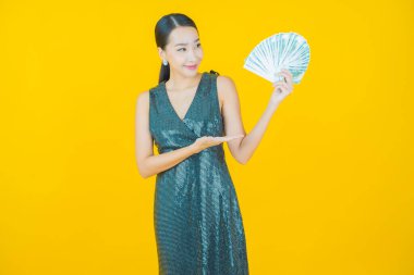 Asyalı güzel bir kadının portresi. Renkli arka planda bol para ve parayla gülümsüyor.