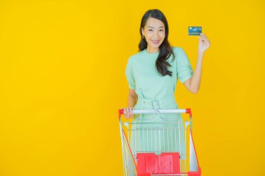 Renkli arka planda süpermarketten alınmış market sepetiyle gülümseyen güzel Asyalı kadın portresi.
