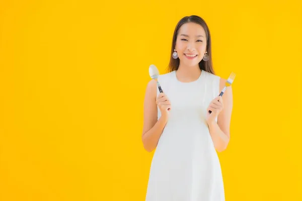 노란색외진 배경에 숟가락을 아름다운 아시아 여자의 — 스톡 사진