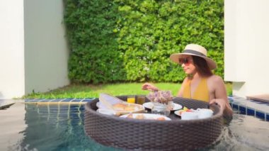 Otelde yüzme havuzunda dinlenen Asyalı güzel bir kadının görüntüsü.