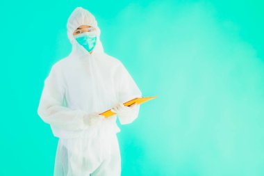 Güzel, genç Asyalı doktor kadın koronavirüsten korunmak için ppe ya da kişisel koruyucu ekipman takıyor ya da mavi izole arka planda beyaz kartı olan 19. bölgede yaşıyor.