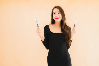 Kaşığı ve çatalı olan güzel Asyalı bir kadının portresi izole edilmiş renkli arka planda yemeye hazır.