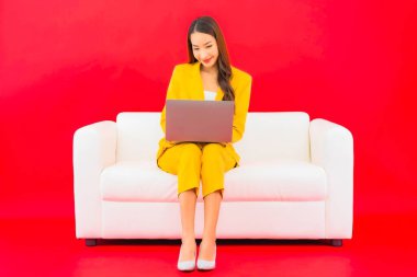 Güzel bir Asyalı kadın portresi kırmızı arka planda bilgisayar bilgisayarı kullanıyor.