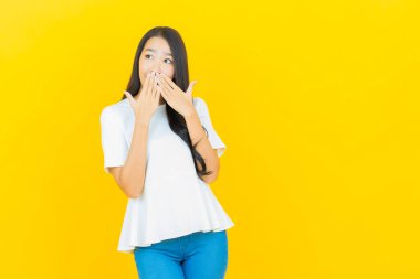 Asyalı güzel bir kadının portresi. Sarı arka planda hareketli gülümsüyor.