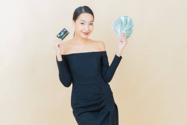 Asyalı güzel bir kadının portresi. Renkli arka planda bol para ve parayla gülümsüyor.