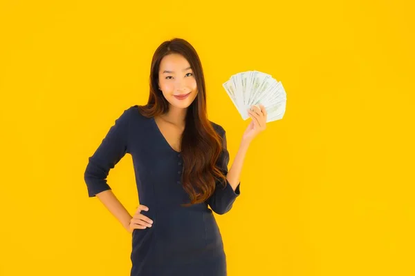 肖像画美しいです若いですアジアの女性とともにお金と現金上の黄色隔離された背景 — ストック写真