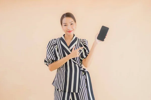 肖像画美しいです若いですアジアの女性とともにスマートフォン上の茶色の背景 — ストック写真