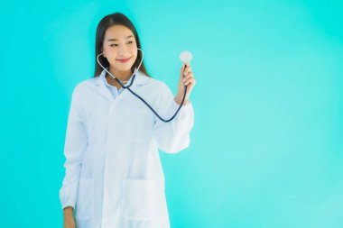 Klinikte ya da mavi izole edilmiş arka planda hastanede kullanmak üzere steteskoplu güzel Asyalı genç doktor kadın portresi.