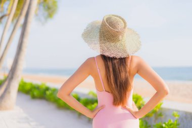 Güzel bir Asyalı kadın portresi. Tatil gezisinde deniz manzaralı açık havuz etrafında rahatça yüzebiliyor.