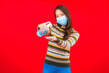 Kırmızı izole edilmiş arka planda alkol jeli güzel Asyalı kadın portresi.