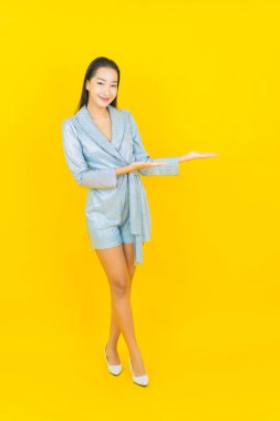 Asyalı güzel bir kadının portresi. Sarı arka planda hareketli gülümsüyor.