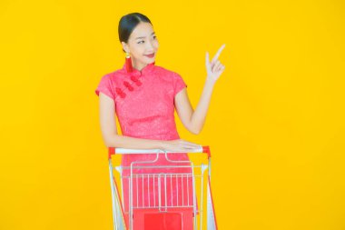 Renkli arka planda süpermarketten alınmış market sepetiyle gülümseyen güzel Asyalı kadın portresi.