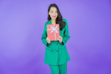 Güzel bir Asyalı kadının portresi. Arka planda kırmızı hediye kutusuyla gülümsüyor.