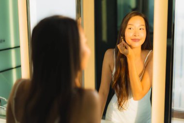 Güzel bir Asyalı kadın portresi makyaj malzemesi makyaj malzemesi ve yüz makyajı ile banyo içinde yüz maskesi.