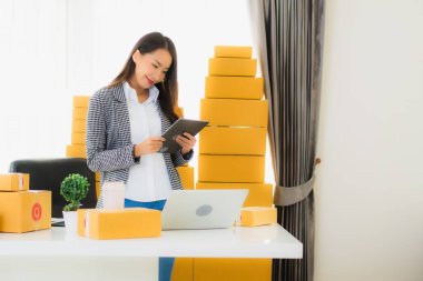 Güzel Asyalı iş kadını portresi evden bilgisayarlı cep telefonuyla karton kutuyla çevrimiçi alışveriş için hazır bekliyor.