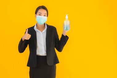 Güzel bir iş kadını portresi. Maske takıyor. Korunmak için alkol jeli kullanıyor.