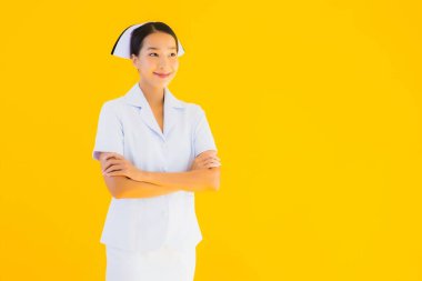 Güzel Asyalı genç Taylandlı hemşirenin portresi klinikteki ve hastanedeki hastalar için sarı izole edilmiş arka planda birçok eylem çalışmasında yer alıyor.