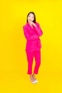 Güzel bir Asyalı kadın sarı arka planda gülümsüyor.