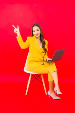 Portre güzel genç iş kadını Asyalı kadın kırmızı arka planda bilgisayar bilgisayarı kullanıyor