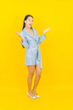 Asyalı güzel bir kadının portresi. Sarı arka planda hareketli gülümsüyor.