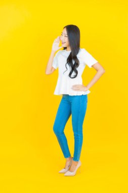 Asyalı güzel bir kadının portresi. Sarı arka planda hareketli gülümsüyor.