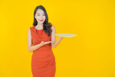 Güzel Asyalı bir kadının portresi. Arka planda boş tabak tabağıyla gülümsüyor.