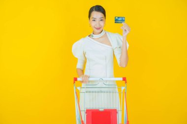 Renkli arka planda süpermarketten alınmış market sepetiyle gülümseyen güzel Asyalı kadın portresi.