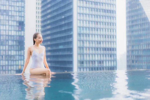 美丽的年轻亚洲女人在酒店度假胜地的室外游泳池边悠闲自在地笑着 — 图库照片