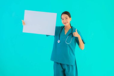 Fotokopi için boş kâğıt tahtası olan güzel Asyalı genç doktor kadın hastane ve klinikteki sağlık hizmetleri konseptinde mavi izole edilmiş arka plan.