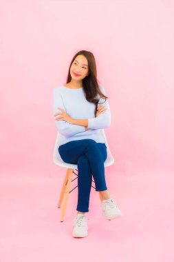 Portrait beautiful young asian woman sit on chair with pink color background