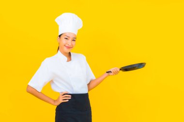 Sarı izole arka planda siyah şapkalı güzel Asyalı şef kadın portresi.