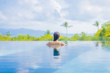 Güzel bir Asyalı kadın portresi gezide deniz manzaralı açık havuzda yüzüyor.