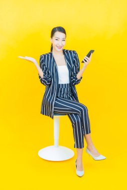 Renkli arka planda akıllı cep telefonuyla güzel Asyalı kadın gülümsemesi