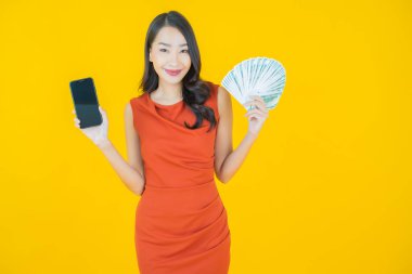 Asyalı güzel bir kadının portresi. Renkli arka planda bol para ve parayla gülümsüyor.